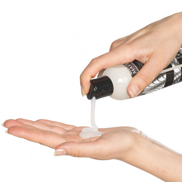 Hand holding a bottle dispensing white cream onto another hand against a white background