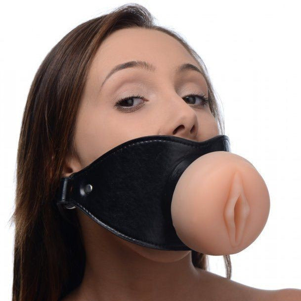 Person wearing a black leather gag with a realistic looking pussy masturbator on a white background