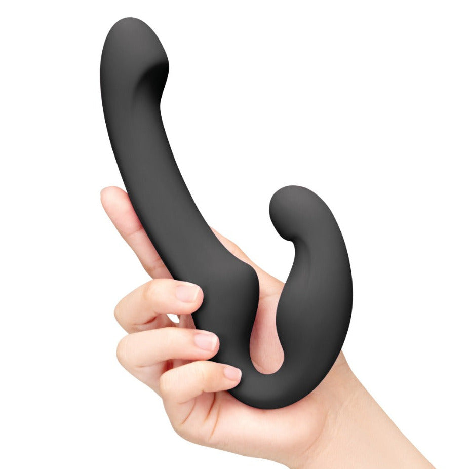 A matte black curved personal massager held in a person's hand against a plain white background.