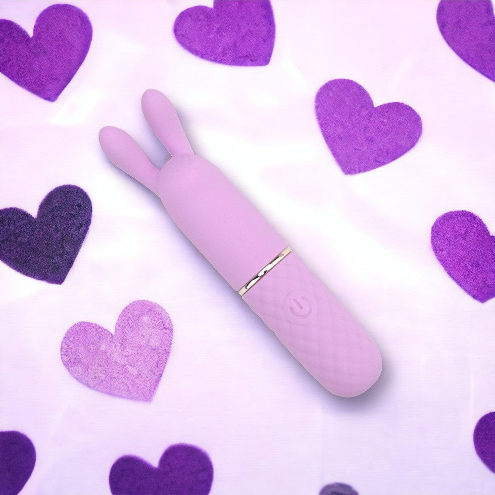 Purple rabbit-shaped sex toy on a white background with purple hearts