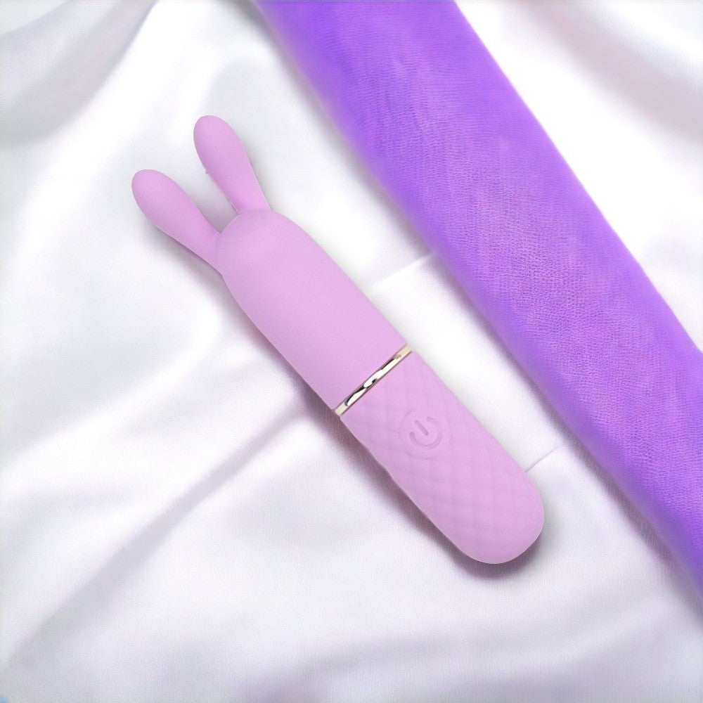 Purple silicone rabbit-shaped massager on a white background
