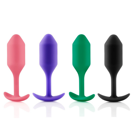 Four silicone butt plugs in coral, purple, green, and black on a white background