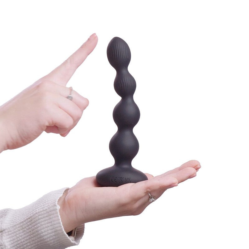Black silicone butt plug held by a hand with a white background