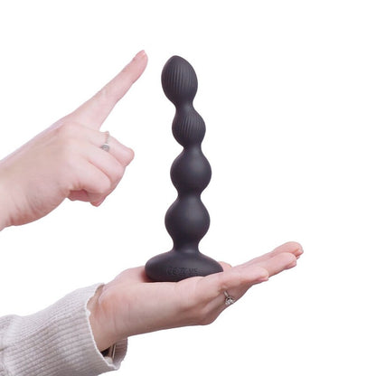 Black silicone butt plug held by a hand with a white background