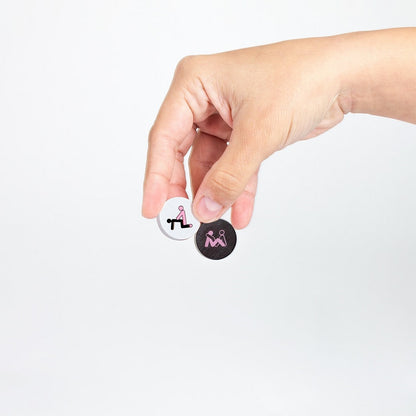 Hand holding two small circular icons with symbols on a white background