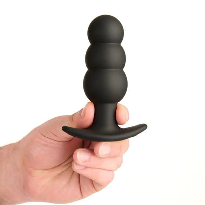 Black silicone butt plug held in a hand against a white background