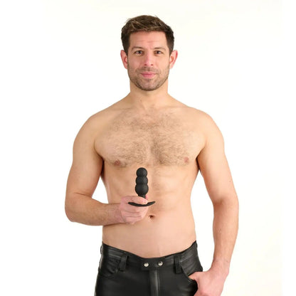 Man holding a black anal butt plug object against a white background
