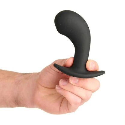 Black silicone butt plug held in a hand on a white background