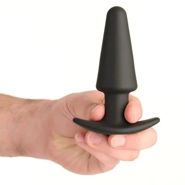 Black silicone butt plug held in a hand against a white background