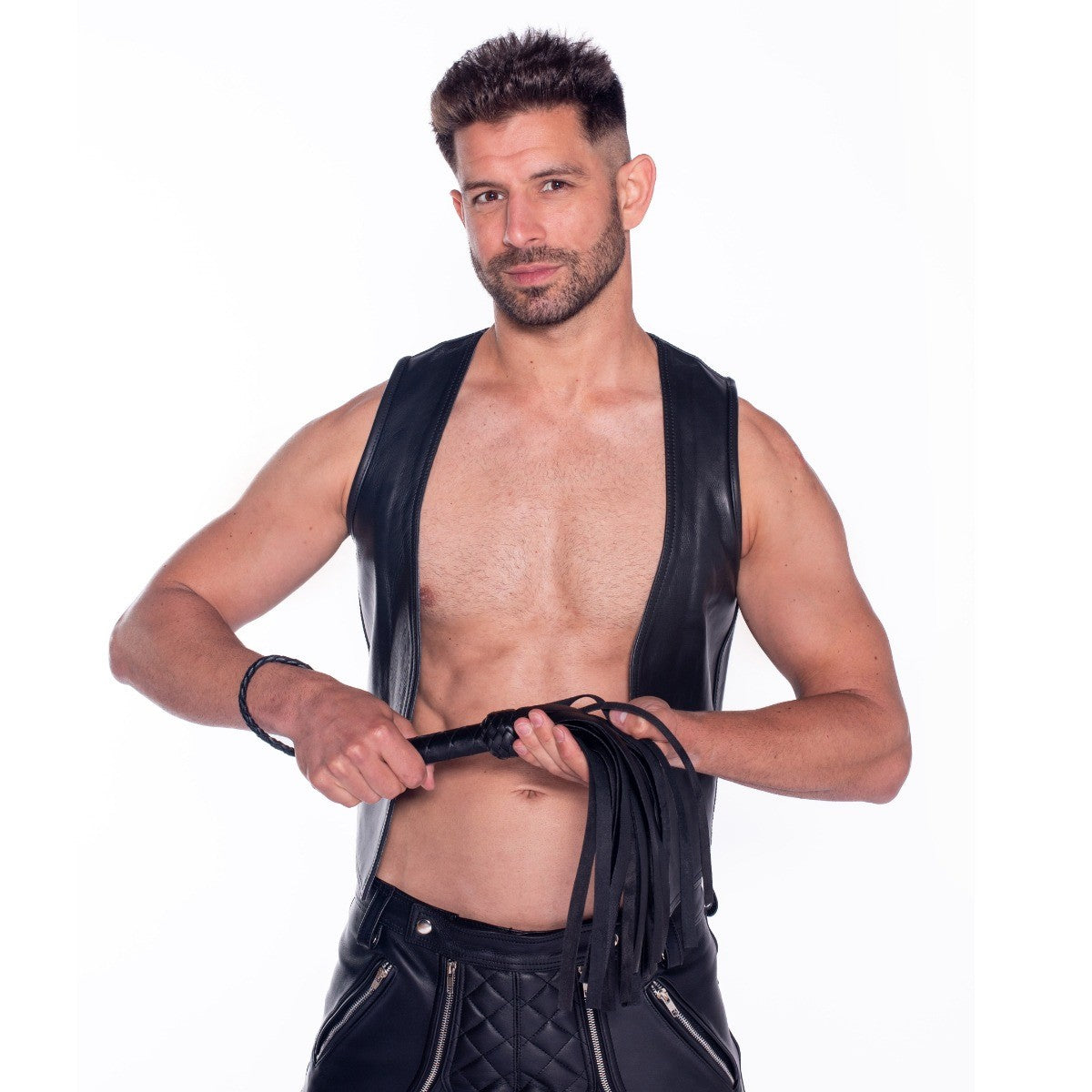 Man wearing a black leather vest with flogger on a white background