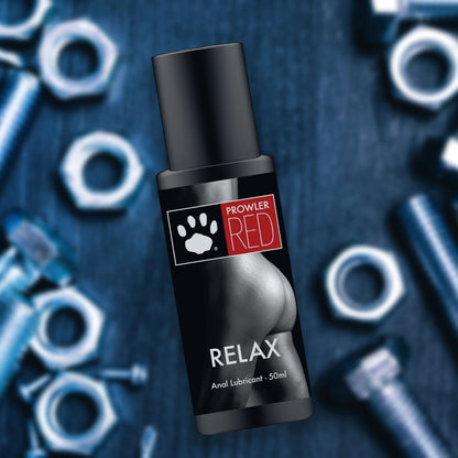 Anal lubricant bottle labeled 'Prowler Red Relax' on a dark background with sexual toys.
