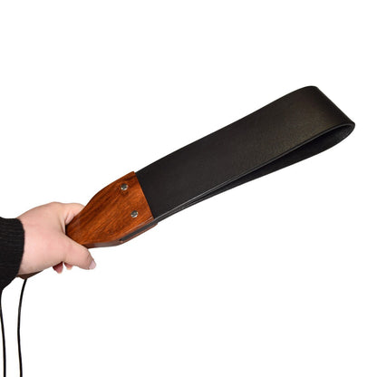 Hand holding a black and wooden paddle against a white background
