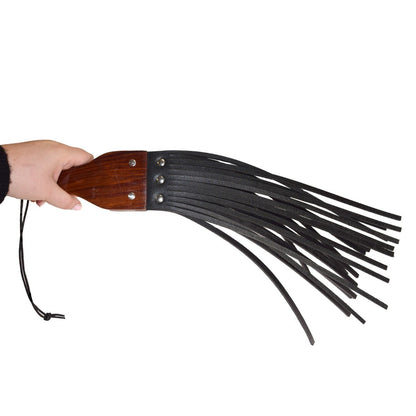 Hand holding a leather flogger with wooden handle on a white background
