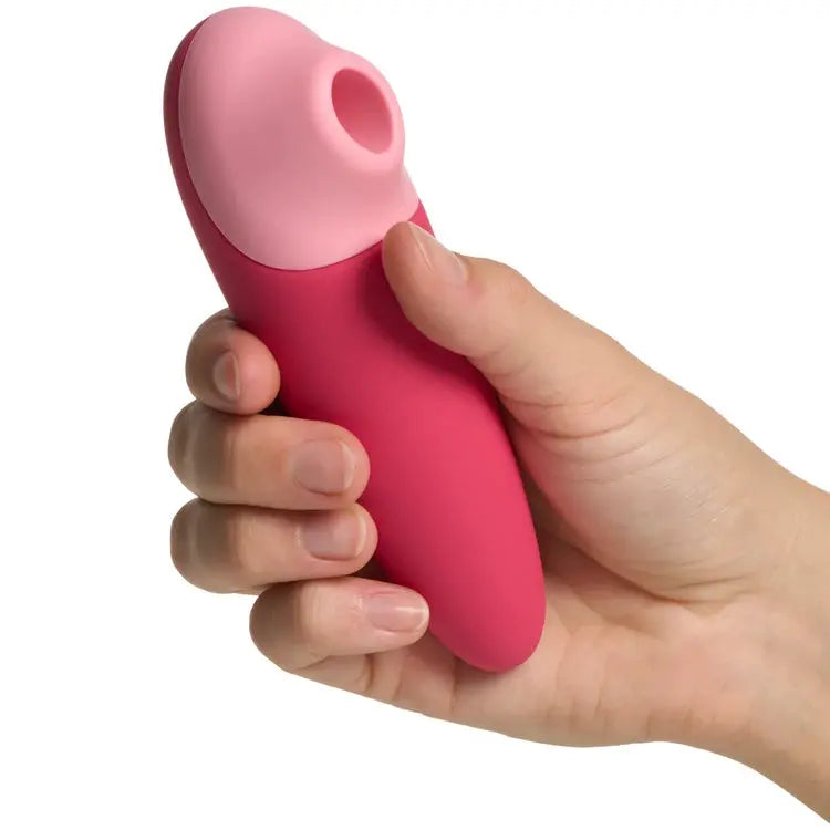 Pink and red silicone massage tool held in a hand against a white background