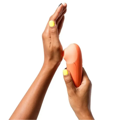 Hand holding an orange electronic device against a white background