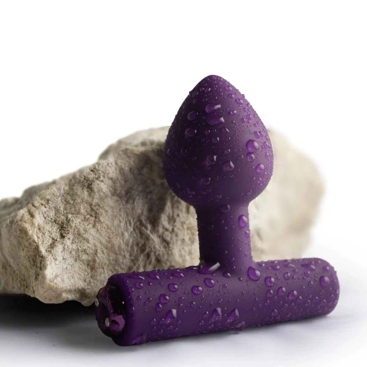 Purple silicone butt plug with water droplets on a white background
