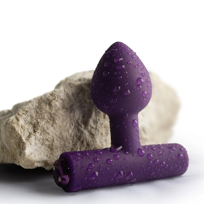 Purple silicone butt plug with water droplets on a white background