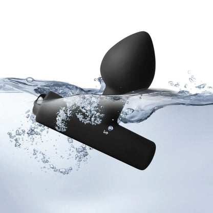 Anal plug partially submerged in water with bubbles around it.