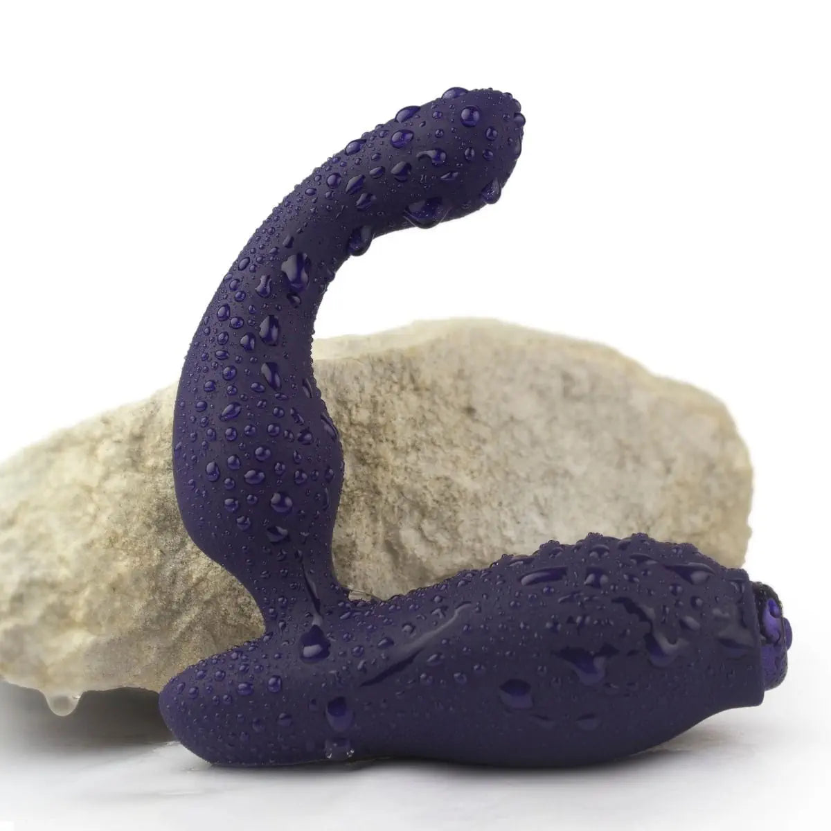 Purple prostate massager with water droplets on a white background