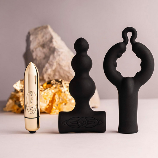 Three black and gold sex toys on a neutral background