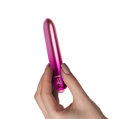Hand holding a pink cylindrical vibrator with a rocks off logo on a white background