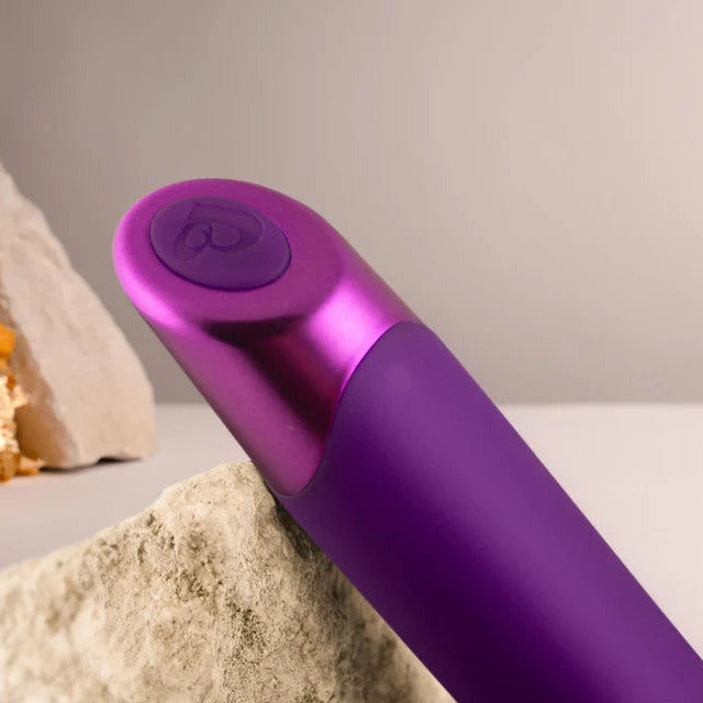 Purple handheld device on a neutral background with rocks