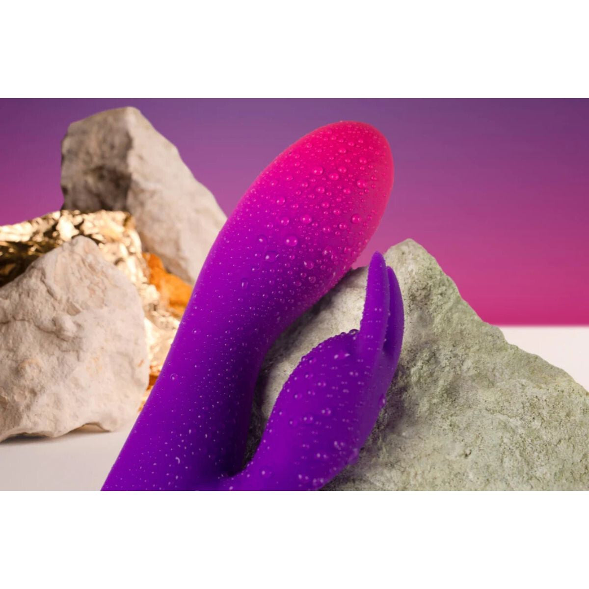 Purple and pink silicone rabbit on rocks with a purple background
