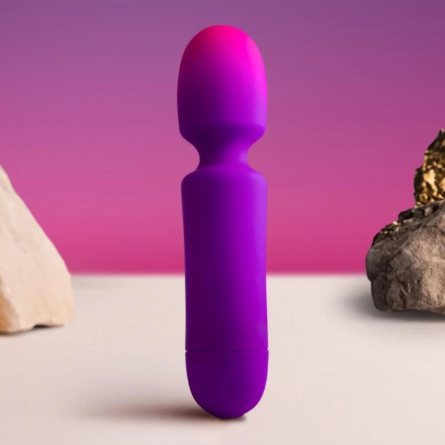 Purple silicone bullet vibrator on a surface with rocks and a pink background