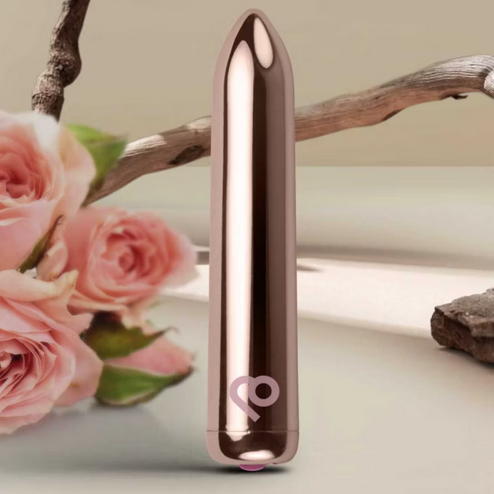 Rose gold bullet vibrator on a neutral background with pink roses and branches.