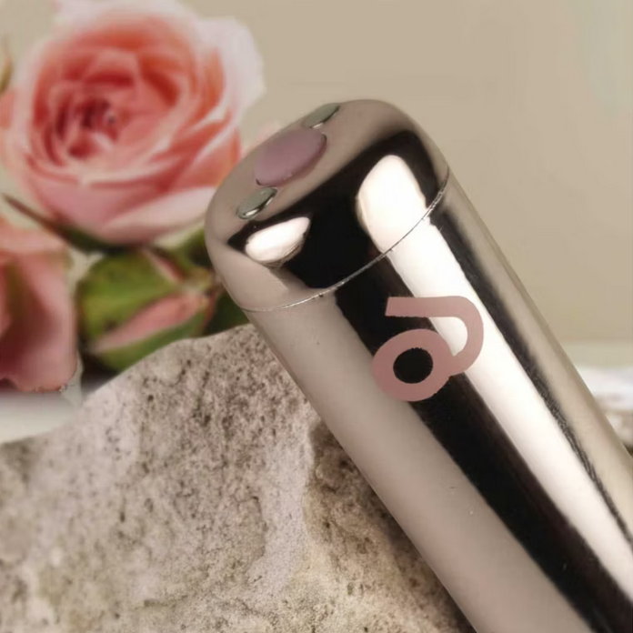 Silver cylindrical product with a logo on a stone surface with pink flowers in the background