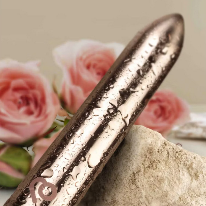 Metallic cylindrical object on a rock with pink roses in the background