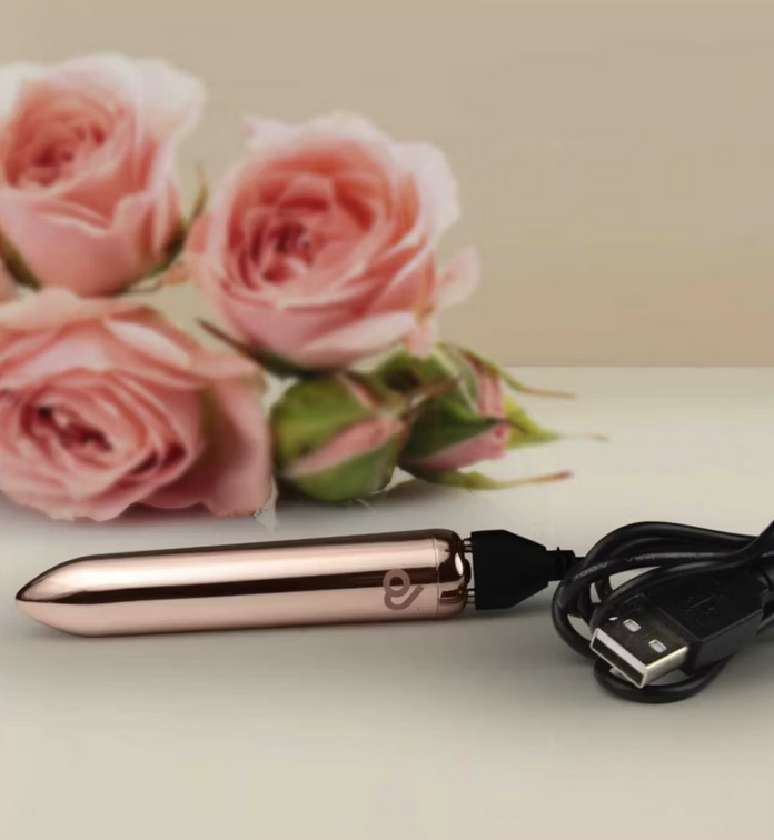 Rose gold electronic device with USB cable on a light surface with pink roses in the background