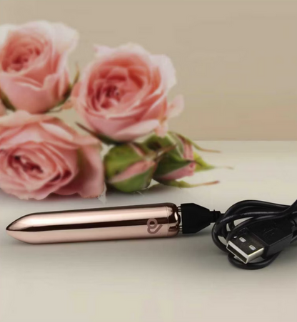 Rose gold electronic device with USB cable on a light surface with pink roses in the background