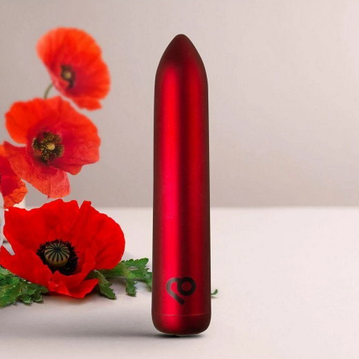 Red cylindrical bullet vibrator with a brand logo next to red flowers on a light background