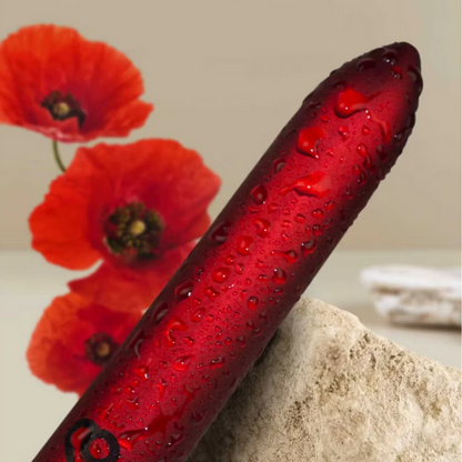 Red vibrator with water droplets against a background of red flowers and a rock.
