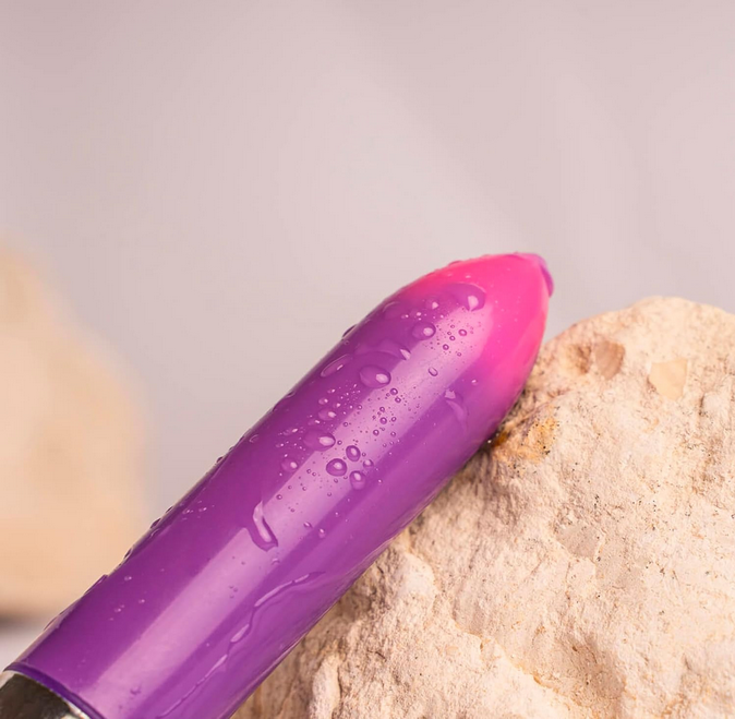 Purple and pink device with water droplets on a rock