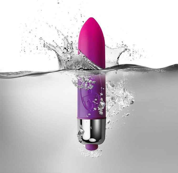 Purple and pink electronic massager partially submerged in water with water splashes.