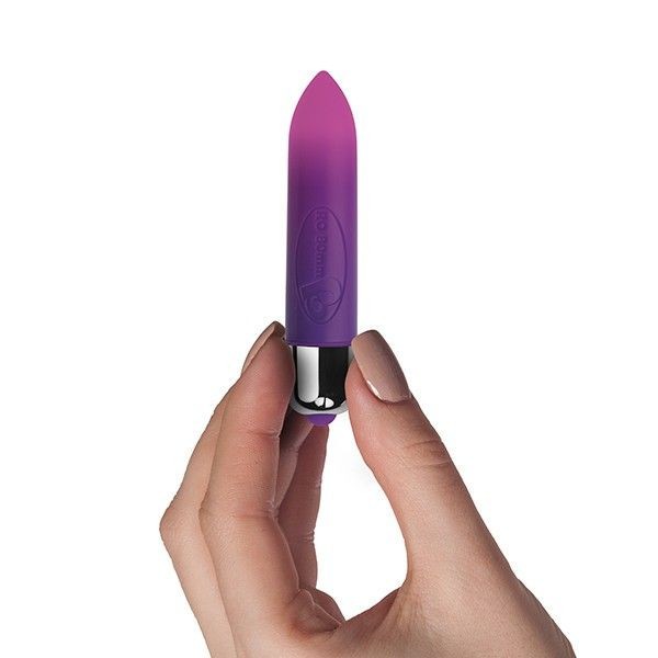 Purple vibrator held in a hand against a white background