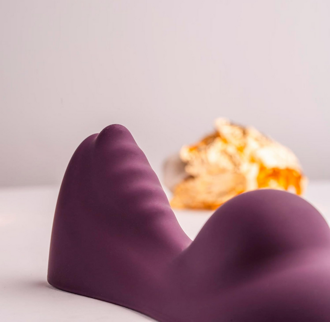 Purple silicone vibrator on a white surface with a blurred background