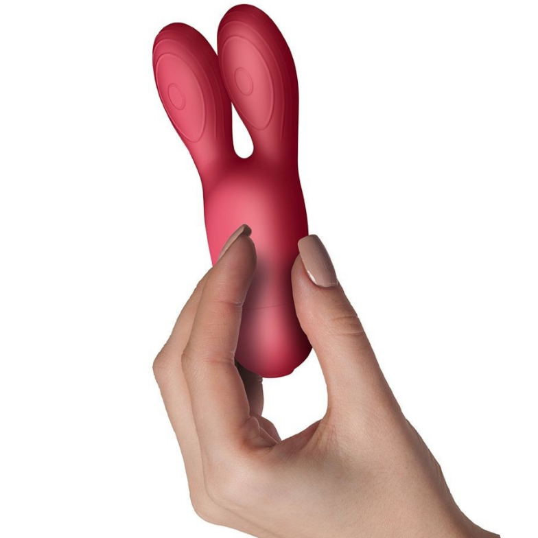 Red silicone rabbit vibrator held by a hand on a white background