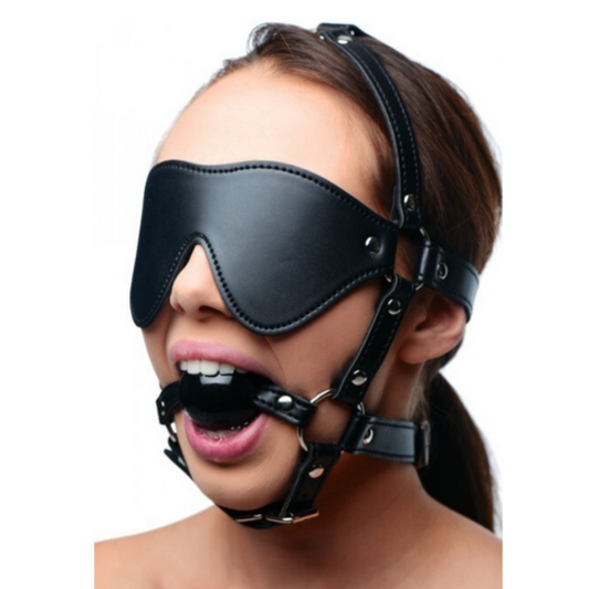 Person wearing a black leather muzzle and blindfold on a white background