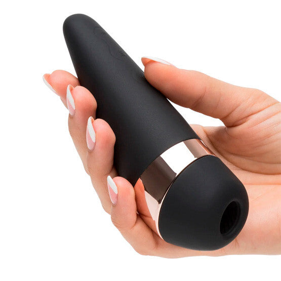 Black and gold electronic device held in a hand with a white background