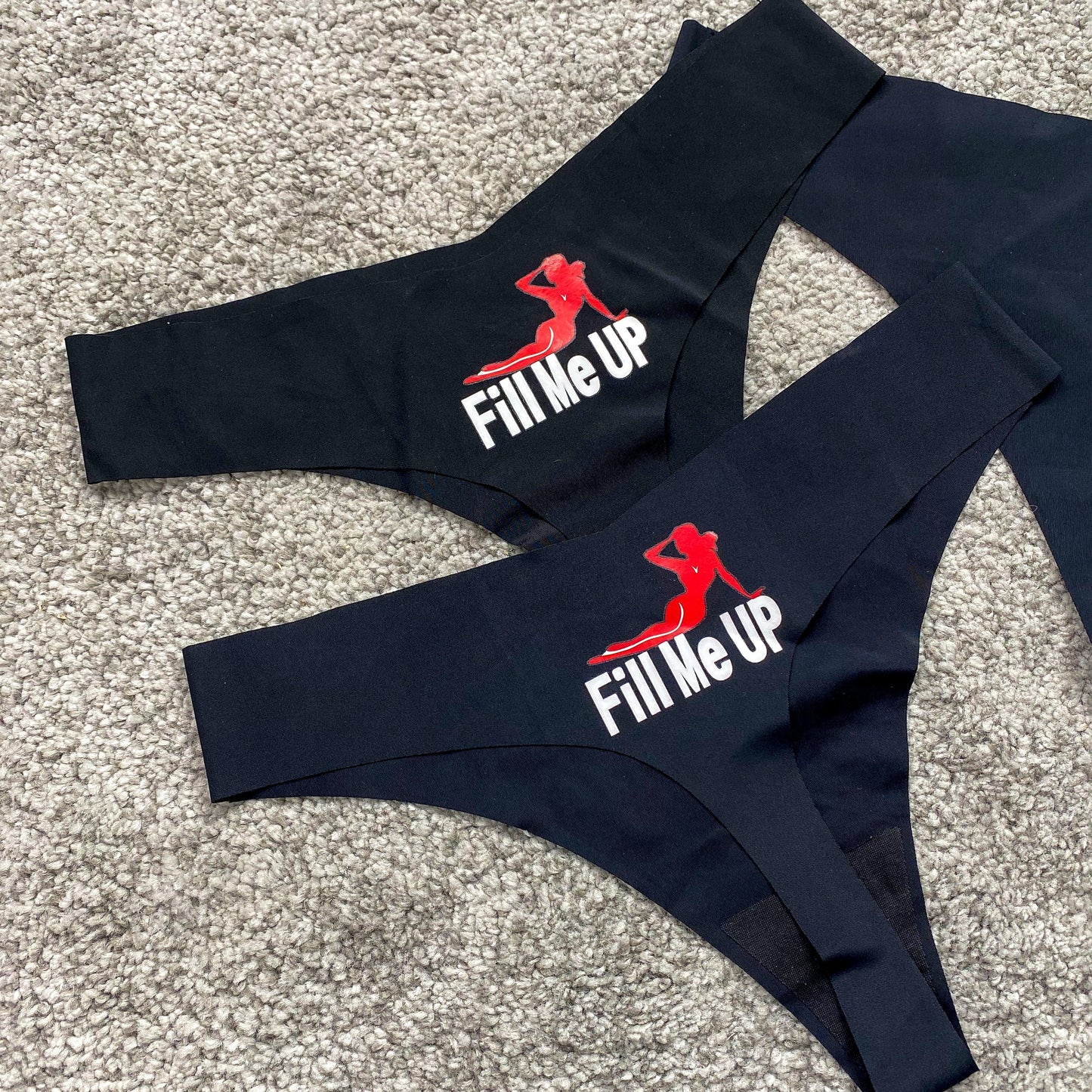 Black swimwear set with 'Fill Me Up' text and logo on a textured surface