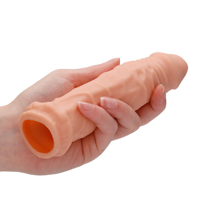 Shots Toys RealRock Skin 6 Inch Penis Sleeve Extender Light in a hand on a white background