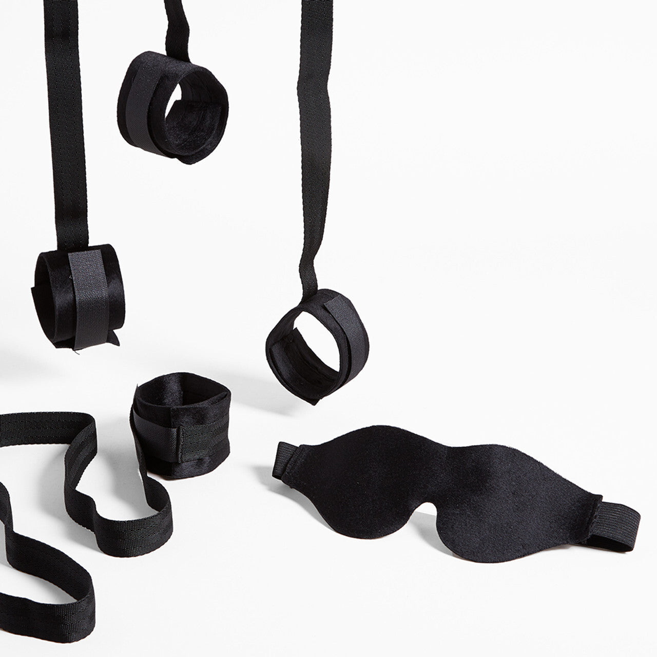 Black bondage cuffs and blindfold on a white background