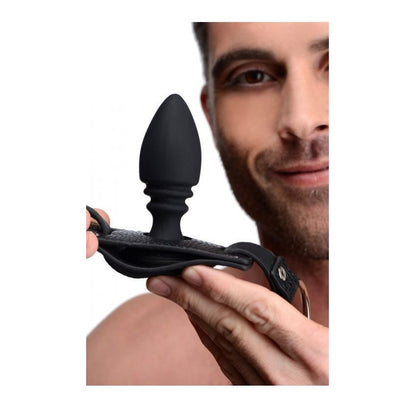 Person holding a black silicone butt plug with a plain background