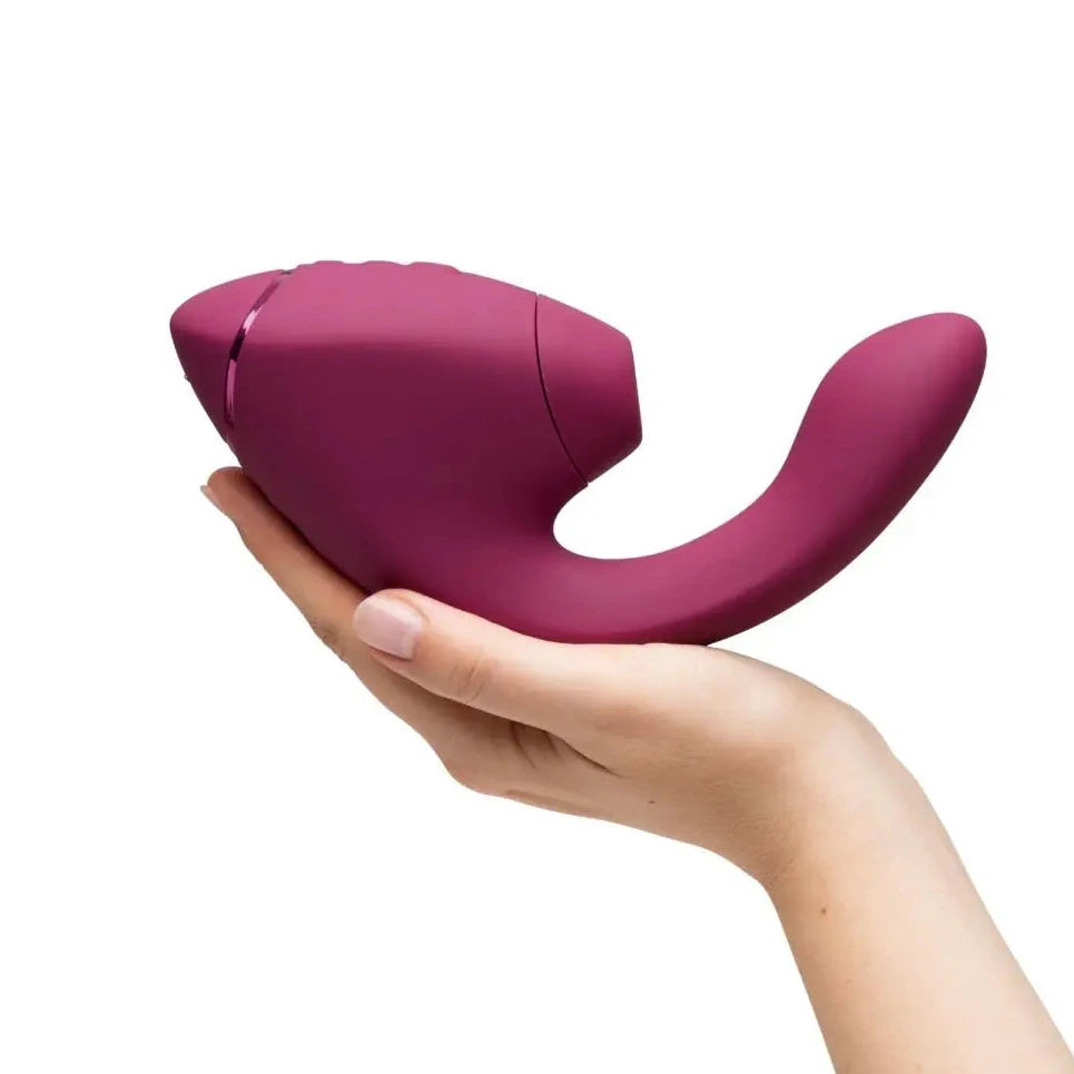 Hand holding a pink silicone massage product on a white background
