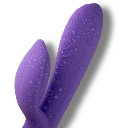 Purple silicone rabbit-shaped sex toy with water droplets on a white background