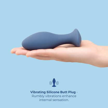 Blue vibrating silicone butt plug held in a hand against a light blue background