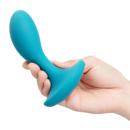 Turquoise silicone anal massager held in a hand against a white background
